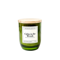 Green candle with a wooden lid labeled 'Cabin in the Woods' on a white background